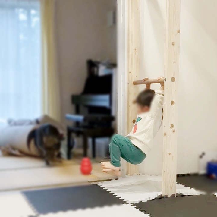 うんていやぐら(室内雲梯)の鉄棒スタンドに子供がぶら下がって遊んでいる様子